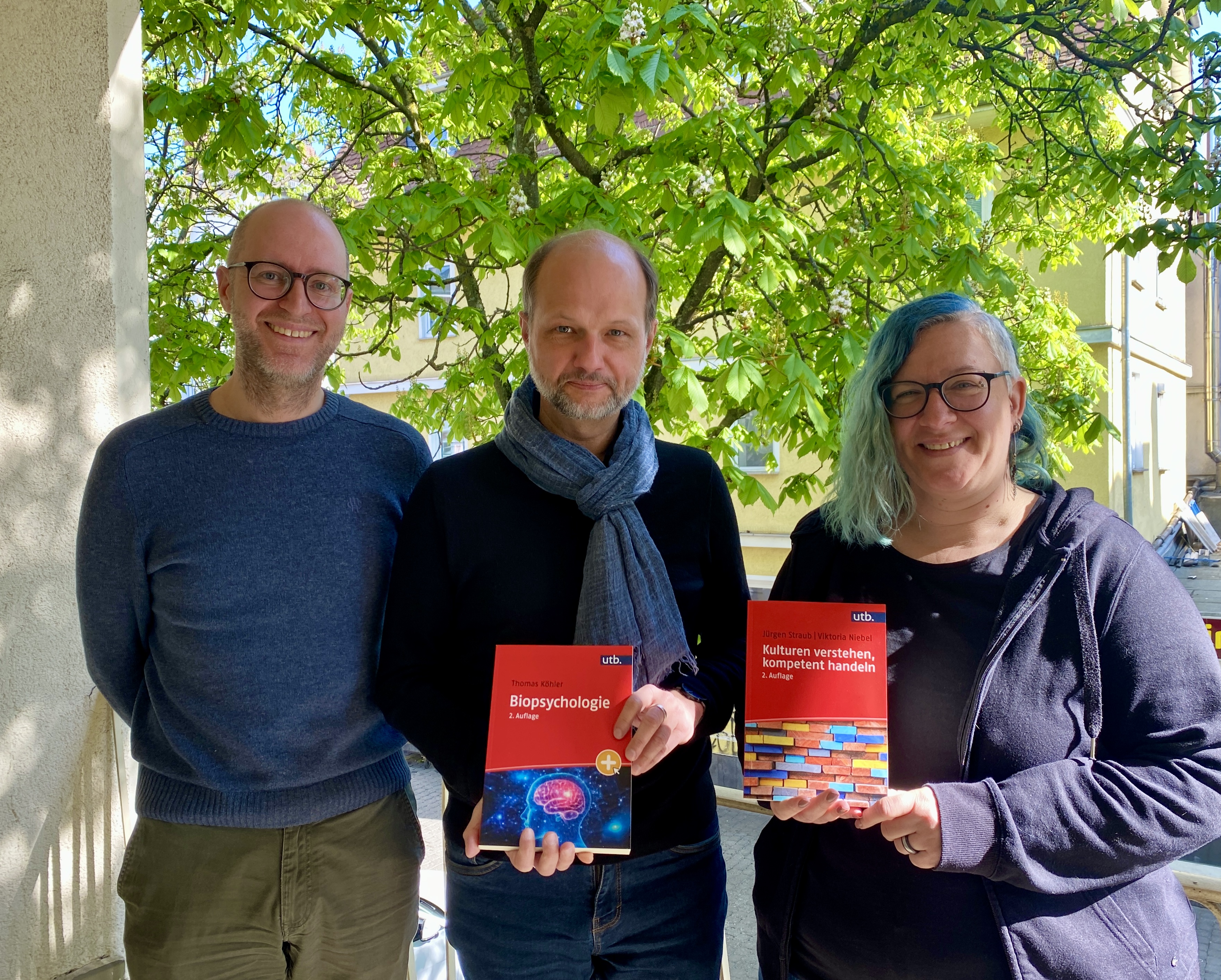 Johann Wirth (Verleger), Christian Flierl (Lektorat/Manuskriptangebote/Rechte & Lizenzen) und Grit Sündermann (Leitung Lektorat und Herstellung) halten die beiden ersten utb-Bände des Psychosozial-Verlags hoch